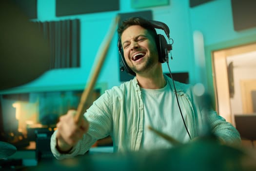 Musician, headphones and man drummer playing in a recording studio for production of a song. Musical artist, drums and male with a passion for music with a percussion instrument for entertainment.