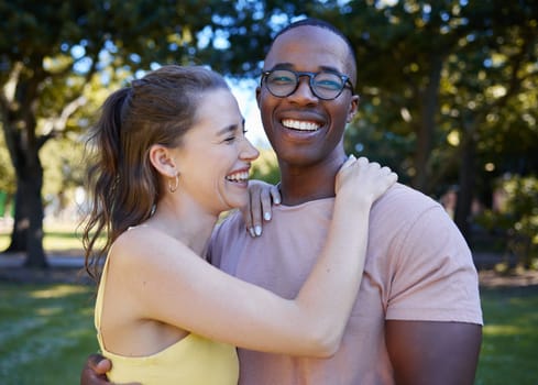 Summer, love and laugh with an interracial couple hugging outdoor together in a park or garden. Nature, diversity and romance with a man and woman bonding while on a date outside in the countryside.