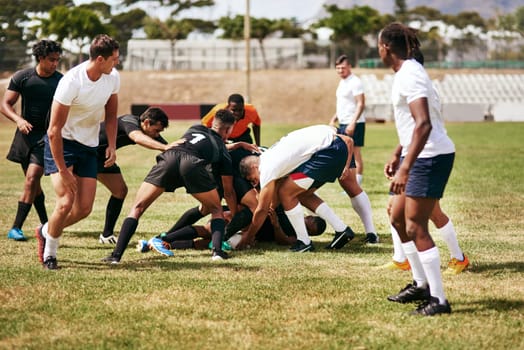 Brace yourself, rugby can be brutal. a group of young men playing a game of rugby.