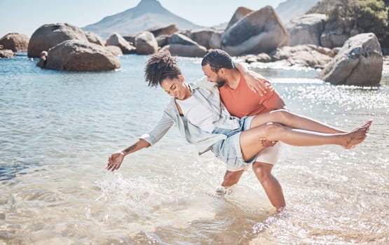 Love, water and playful black couple at the beach enjoy summer vacation, holiday and weekend. Travel, nature and man carrying woman standing in ocean having fun, bond and spend quality time together