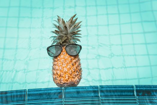 Summer Vacation and Swimming Pool Relaxation Lifestyles Concept, Pineapple With Sunglasses in Poolside at The Beach Vacations. Tropical Leisure Activities Relaxing and Holiday Resort