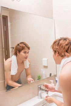 Man washing his face in the bathroom washbasin
