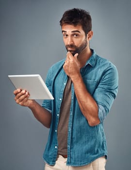 When your friend posts something borderline inappropriate. Studio shot of a handsome young man using a digital tablet against a grey background.