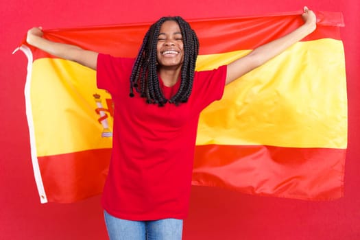 Happy african woman raising a spanish national flag