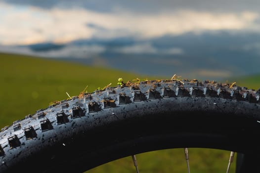 Concept mtb downhill bike theme. Close-up of the tread of an all-terrain mountain bike tire against the backdrop of mountains and sunset sky