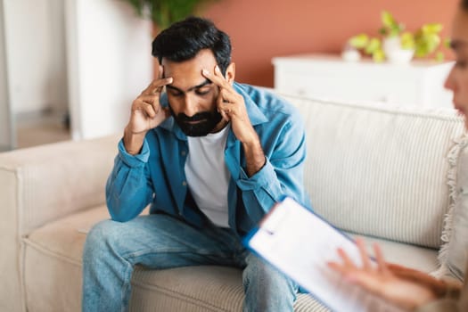 Unhappy Indian Man With Depression Sitting At Psychotherapy Session Indoor