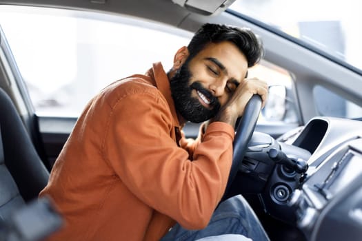 Indian Man Hugging Wheel Of Auto Sitting In Driver's Seat