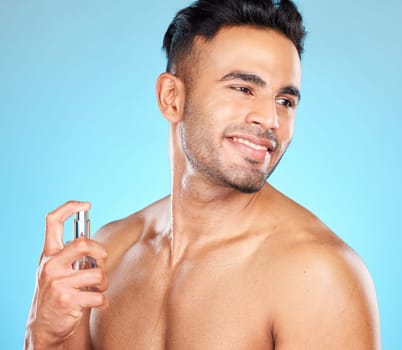 Man, happy and perfume for fragrance, aroma and manly scent on blue studio background. Young male, healthy Latino gentleman and cologne for natural beauty, fresh and smell good for hygiene and relax