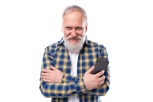 handsome 50s elderly gray-haired man with a beard masters a smartphone on a white background
