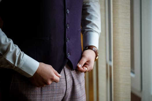 Man puts on a wedding suit and accessories on the wedding day.