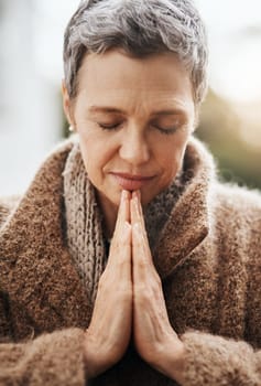 Senior woman is praying, hands with worship and religion, God with peace, gratitude and faith outdoor. Spiritual female person in nature with face, eyes closed and prayer for guidance and blessing