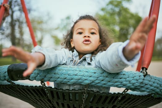 Young girl play in playground, park and outdoor with portrait, fun and early childhood development with toddler. Kid, freedom and swing, playful and playing during holiday and growth in nature