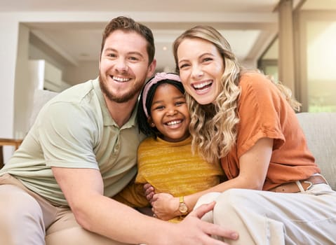 Adoption, love and parents with a hug for child on the sofa in the living room of family home. Happy, care and portrait of African girl kid with affection from mother and father in interracial house