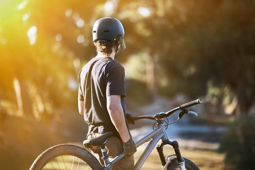 Bike, exercise and summer with a sports man outdoor in nature for leisure or recreation in summer. Back, bicycle and fitness with a male athlete standing on an open green field carrying his transport