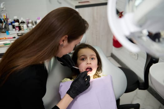 Female dentist, dental hygienist examining teeth of a child patient and treating caries. Oral health and hygiene concept