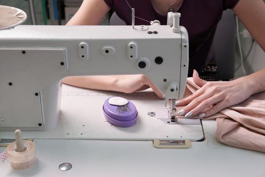 dressmaker using sewing machine in tailor studio, modern atelier shop