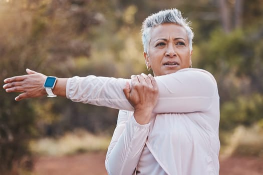 Exercise, stretching and senior woman outdoor in nature for running, cardio fitness and a workout with a smartwatch. Elderly female in a forest for cardio training for a healthy lifestyle and body