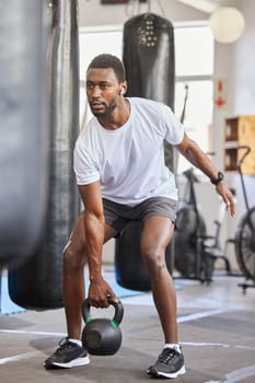 Exercise, kettlebell and black man doing fitness with a weight with strength, focus and motivation. Sports, exercising and strong African male athlete doing muscle training or workout at a gym