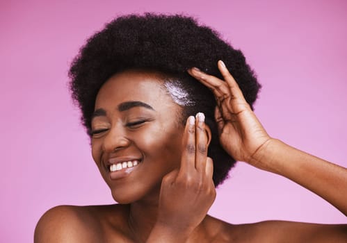 Happy black woman, afro hair and conditioner treatment for ethnic texture on pink studio background. African model, haircare cosmetics and cream product for scalp, skin relaxer and beauty maintenance.
