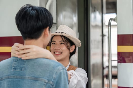 positive girlfriend hugging pleased man while locating near train