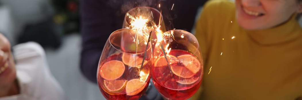 Group of happy people enjoying fireworks party in cocktail glasses