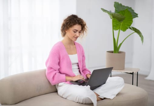 Freelance Concept. Young Woman Using Laptop While Sitting On Couch At Home