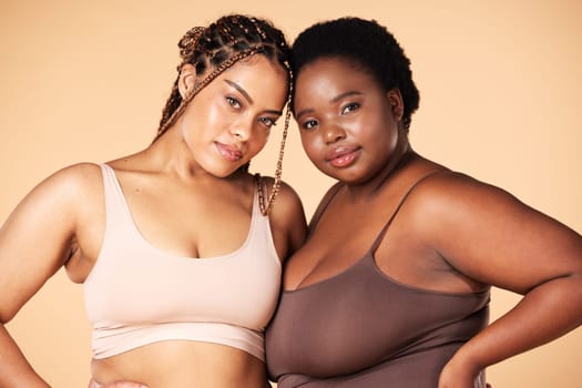 Portrait, beauty and plus size with black woman friends in studio on a beige background for body positivity. Makeup, diversity or wellness with a model female and friend posing to promote inclusion