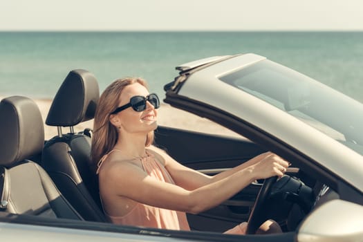 Young woman drive a car on the beach