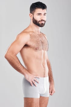 Exercise, body and underwear with a man model in studio on a gray background for health or grooming. Aesthetic, muscle and manly with a handsome young male posing to promote wellness or lifestyle