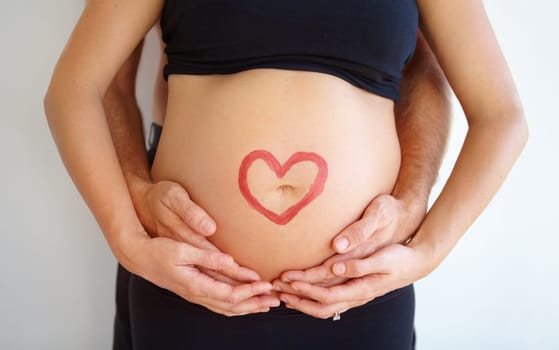 Closeup, pregnant and woman with heart, stomach and bonding with nurture, health and wellness. Zoom, couple and hands with love symbol, support and belly with childcare, pregnancy and wellness