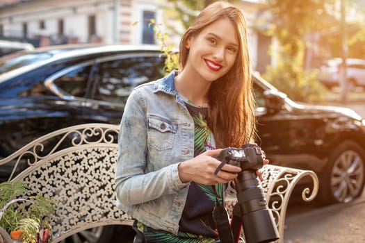 Portrait of professional female photographer on the street photographing on a camera.