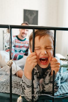 Portrait of naughty little boy shouting on bed