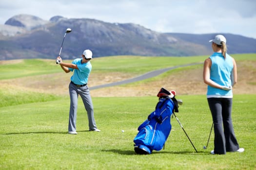 Swing, man or golfer playing golf for fitness, workout or exercise to drive on a green course. Woman, person golfing or athlete training in action or sports game driving with a club stroke on field