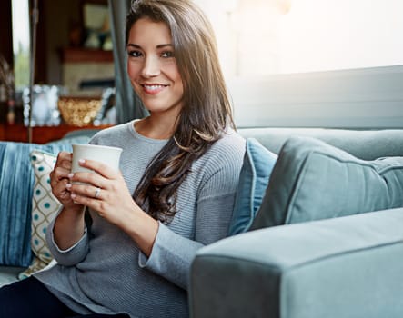 Coffee, woman and portrait of a person at home on a living room sofa with a smile in the morning. Drink, happy person and lens flare on a lounge house couch with tea feeling happiness in a room
