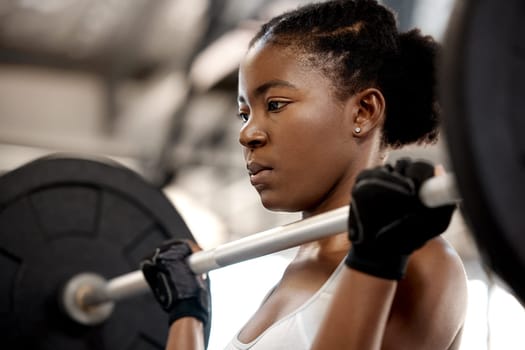 Focus, weightlifting and barbell with black woman in gym for workout, strong and muscle. Health, challenge and exercise with female bodybuilder and weights for fitness, performance and commitment