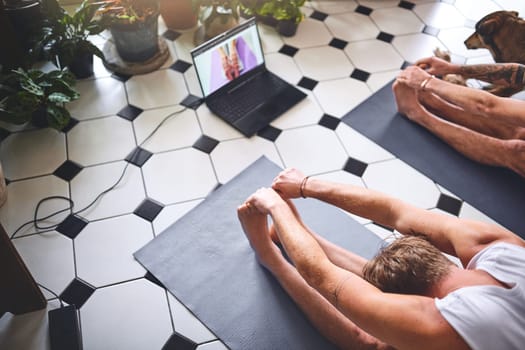Another day another new yoga video. two men using a laptop while going through a yoga routine at home.