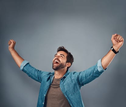 Happy man, fist and celebration for winning, success or achievement against a grey studio background. Male person screaming in victory, win or accomplishment in motivation for goals on mockup space