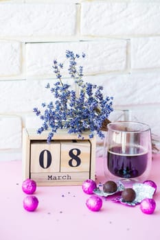 Wooden calendar and a cup of coffee with sweets on the table. Celebration of International Women's Day on March 8