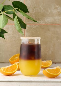 Cold coffee with orange juice in a transparent glass and orange slices