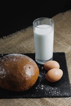 Delicious round rye bread with milk and eggs on a dark background. Crispy fresh bread.