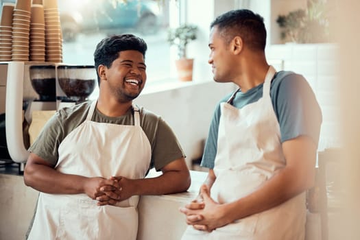 Coffee shop, happy and male barista talking to his colleague before work at a restaurant or cafe. Happiness, smile and men waiter or server in discussion or conversation at the counter by cafeteria.