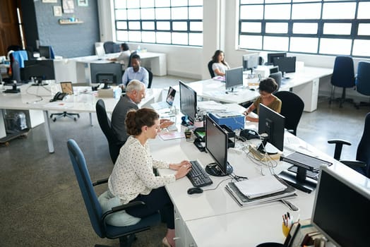 Their strategy for success is hard work. Shot of a group of coworkers sitting at their workstations in an office.
