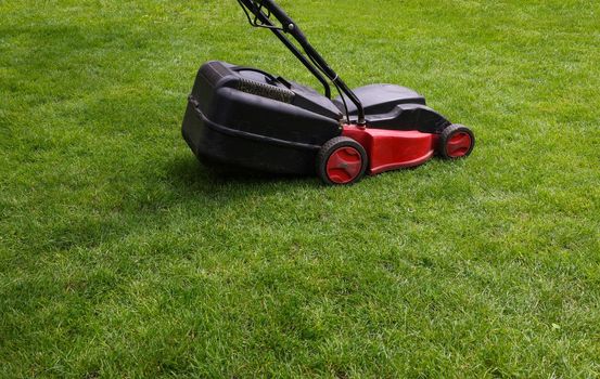 Electric mower over green grass lawn
