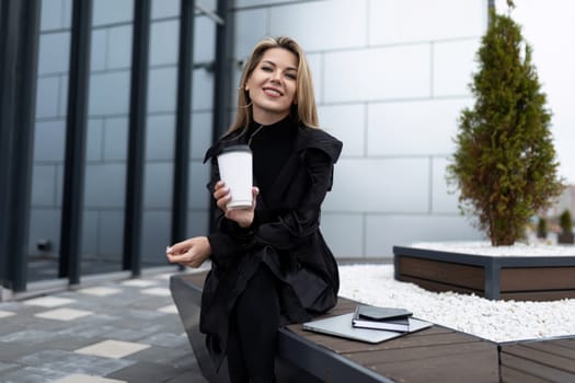 businesswoman resting on the street and drinking coffee