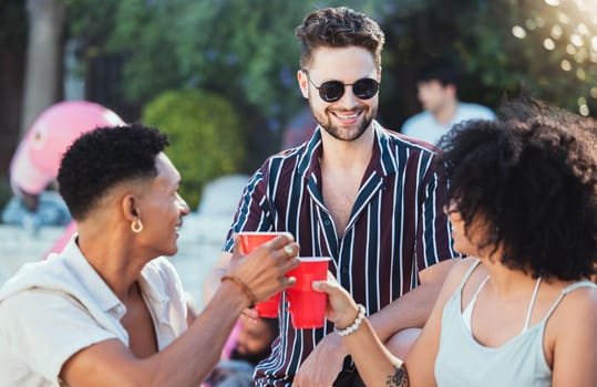 Party, diversity and cheers with friends outdoor together in summer for a social gathering or celebration event. Alcohol, toast or birthday with a young man and woman friend group celebrating outside