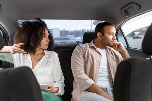 Eastern couple having conflict sitting on back seat in automobile