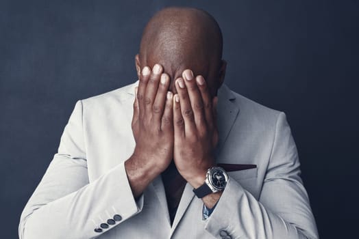 And just that he lost it all. Studio shot of a businessman covering his face against a gray background.