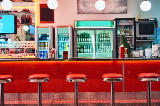 Retro, vintage and stools with interior in a diner, restaurant or cafeteria with funky decor. Trendy, old school and chairs by a counter or bar in groovy, vibrant and stylish old fashioned empty cafe