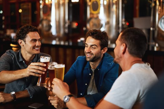 Beer, cheers and men drinking with friends at social event in a restaurant with happiness. Alcohol, glasses and toast at a pub at happy hour with smile and conversation with drinks and celebration