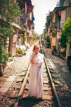 Travel keeps the soul fulfilled. a young woman walking on train tracks through the streets of Vietnam.